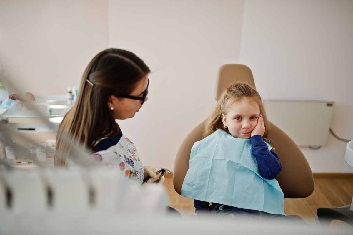 A little girl comfortably sitting in a dentist chair, ready for her dental check-up with a gentle smile.